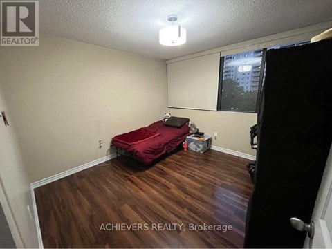 A bedroom with a red bed and wooden floors.