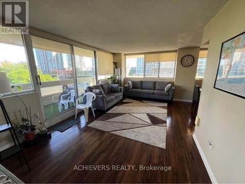 A living room with a couch, chairs, and a rug in front of a large window.