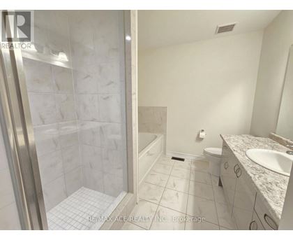 A white bathroom with a walk in shower and a toilet.