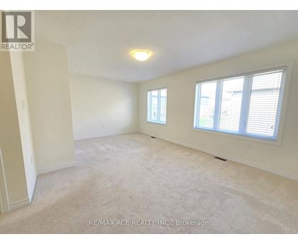 A spacious room with a carpeted floor, two windows, and a ceiling light fixture.