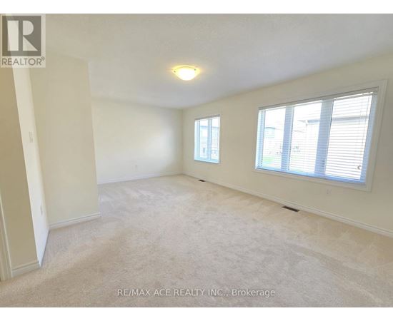 A spacious room with a carpeted floor, two windows, and a ceiling light fixture.