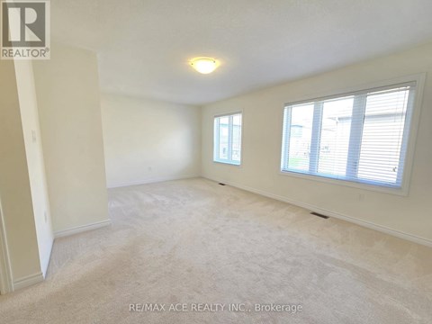 A spacious room with a carpeted floor, two windows, and a ceiling light fixture.