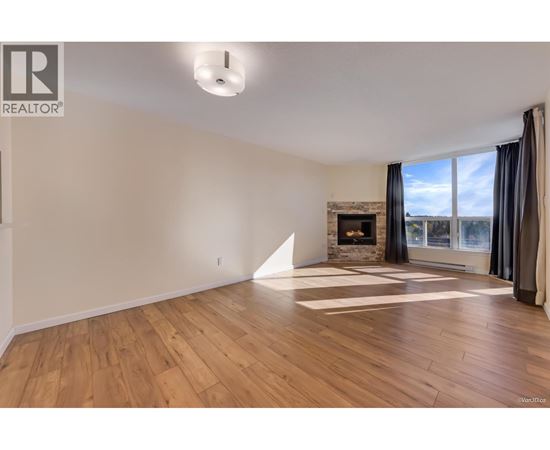 A large, empty room with wooden floors and a fireplace.
