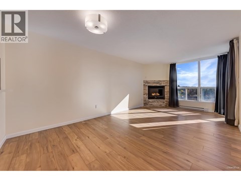 A large, empty room with wooden floors and a fireplace.