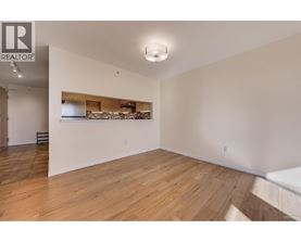 A large empty room with wooden flooring and a white wall.