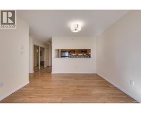 A spacious room with wooden flooring and a bar area in the background.