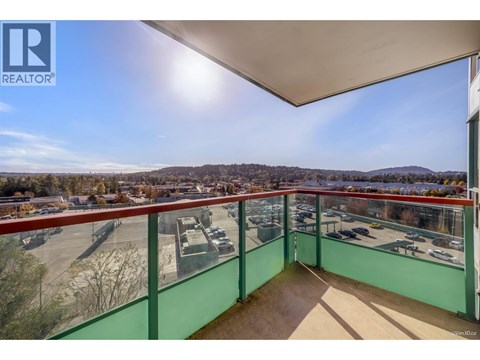 A balcony with a view of a parking lot and trees.