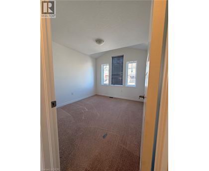 A room with a carpeted floor and a window with blinds.