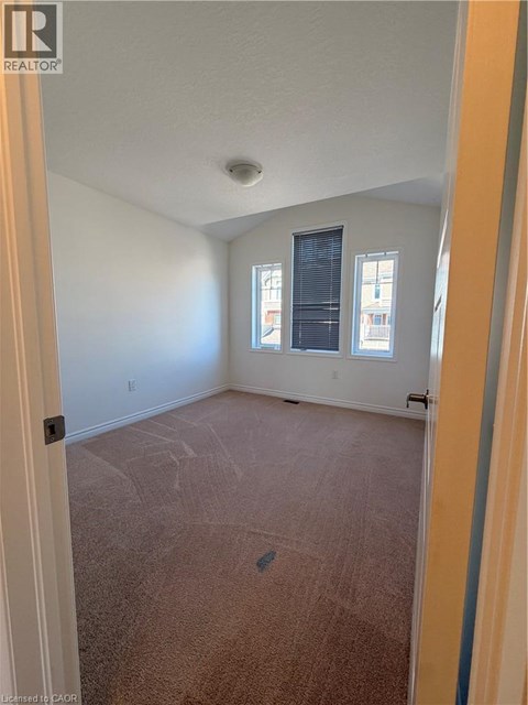 A room with a carpeted floor and a window with blinds.