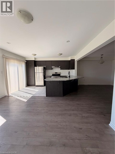 A spacious kitchen with dark wood floors and a large island.