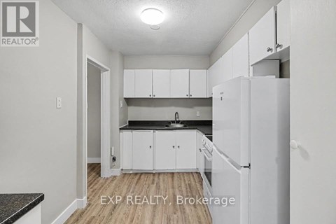 A kitchen with white cabinets and a black countertop.