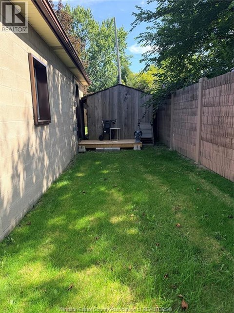A backyard with a wooden fence and a small patio area.