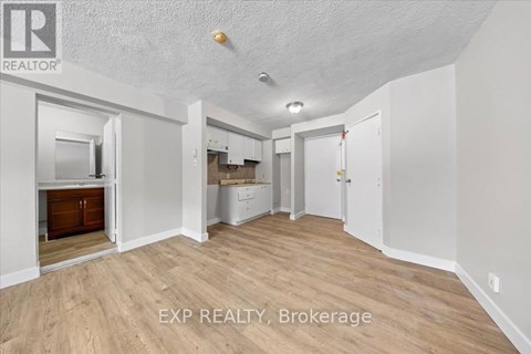 A room with wooden flooring and white walls, with a door on the right side.