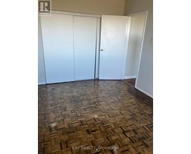 A room with a wooden floor and three white doors.