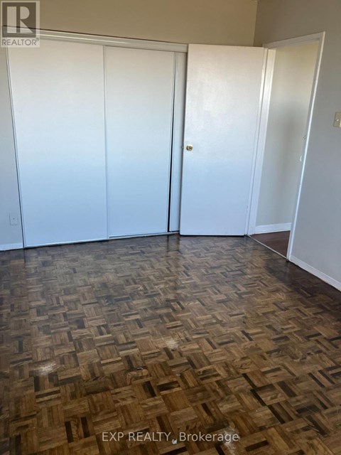 A room with a wooden floor and three white doors.