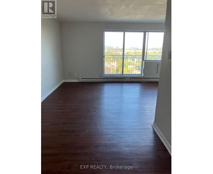 A room with wooden floors and a large window overlooking a balcony.