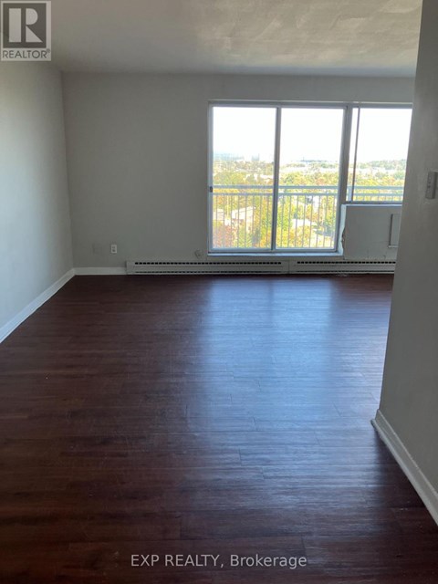 A room with wooden floors and a large window overlooking a balcony.