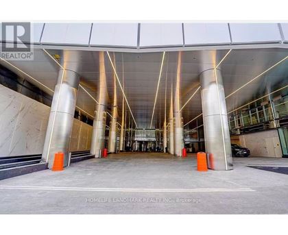 A modern building entrance with a glass wall and a car parked in front.