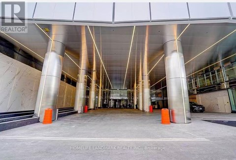 A modern building entrance with a glass wall and a car parked in front.