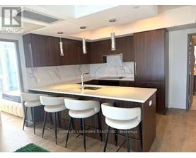 A kitchen with a marble countertop and white bar stools.