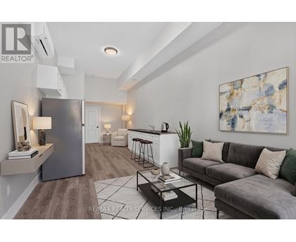 A modern living room with a grey couch and a large abstract painting on the wall.