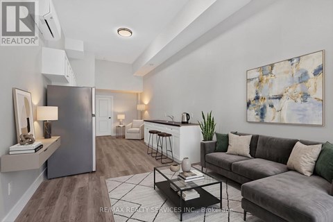 A modern living room with a grey couch and a large abstract painting on the wall.
