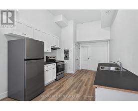 A kitchen with a black counter top and a black refrigerator.