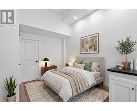 A bedroom with a bed, nightstand, and a potted plant.