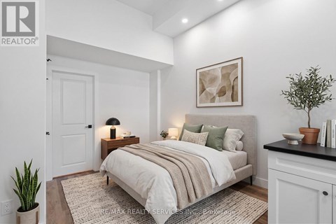 A bedroom with a bed, nightstand, and a potted plant.