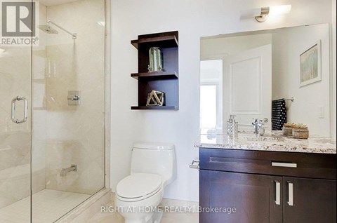 A bathroom with a toilet, a shower, and a vanity.