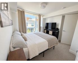 A bedroom with a large bed, a television, and a window with curtains.