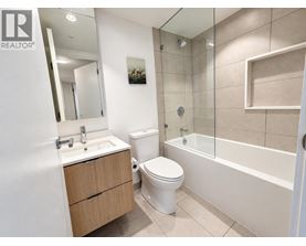 A white toilet sits in a bathroom next to a sink and a bathtub.