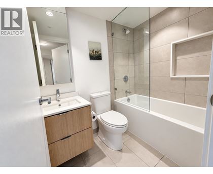 A white toilet sits in a bathroom next to a sink and a bathtub.