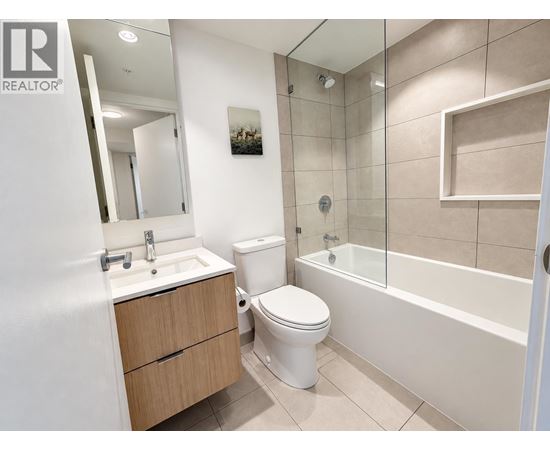 A white toilet sits in a bathroom next to a sink and a bathtub.