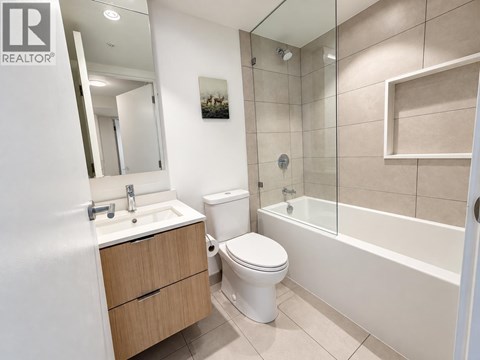 A white toilet sits in a bathroom next to a sink and a bathtub.