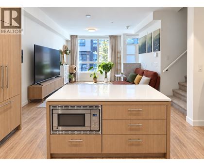 A modern kitchen with wooden cabinets and a microwave oven.