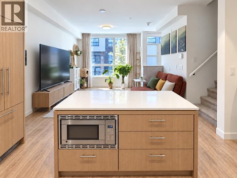 A modern kitchen with wooden cabinets and a microwave oven.