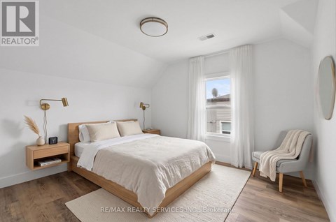 A bedroom with a bed, chair, and window.