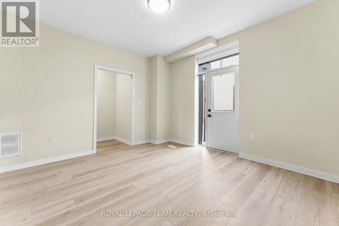 A spacious room with wooden flooring and white walls.