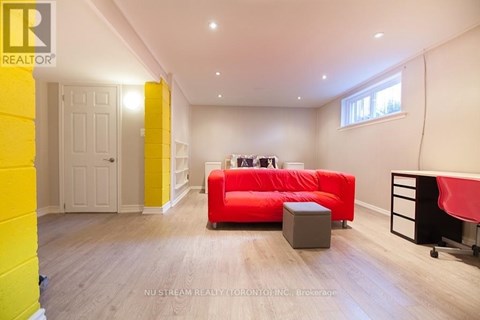 A brightly colored living room with a red couch and a grey ottoman.