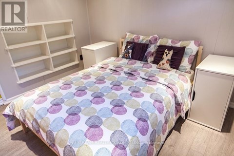 A bedroom with a bed covered in a multicolored bedspread and a white headboard.