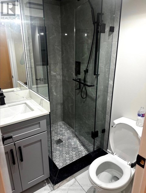 A white toilet is in a bathroom with a walk-in shower.