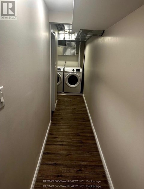 A long hallway with a washer and dryer at the end.