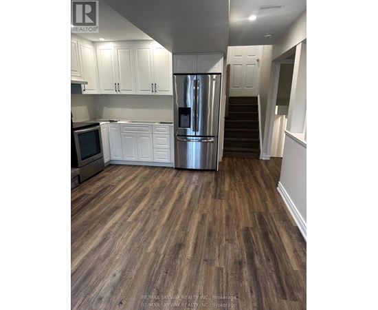 A kitchen with white cabinets and a stainless steel refrigerator.