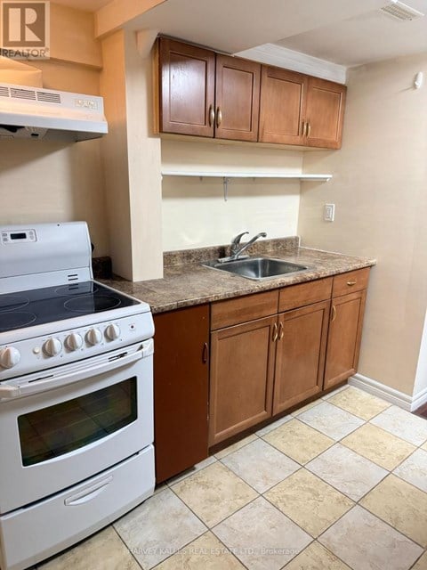 A kitchen with a white stove and wooden cabinets.