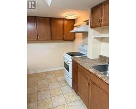 A kitchen with brown cabinets and a white dishwasher.