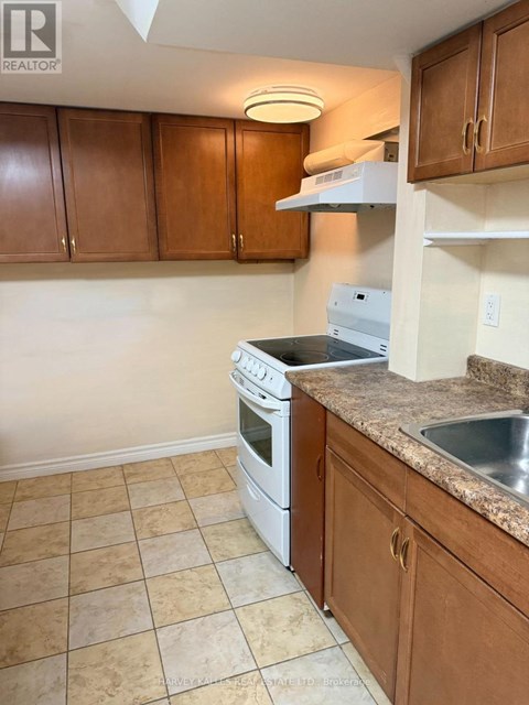A kitchen with brown cabinets and a white dishwasher.