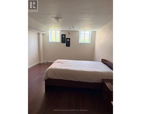 A bedroom with a bed, nightstands, and two windows.