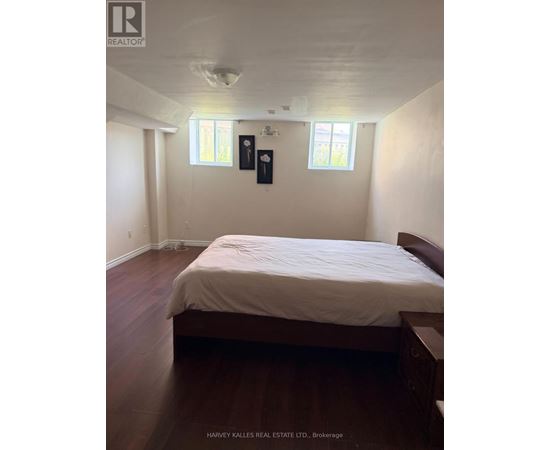 A bedroom with a bed, nightstands, and two windows.