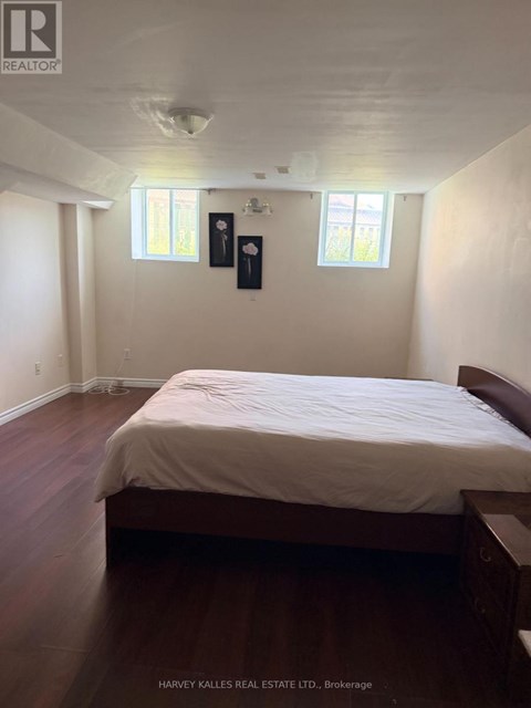 A bedroom with a bed, nightstands, and two windows.